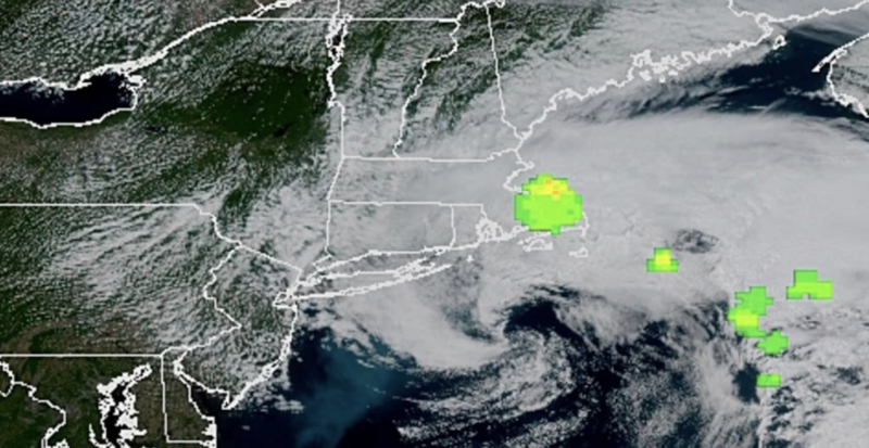 Weather satellite photo with a large green flash in the midst of white clouds.