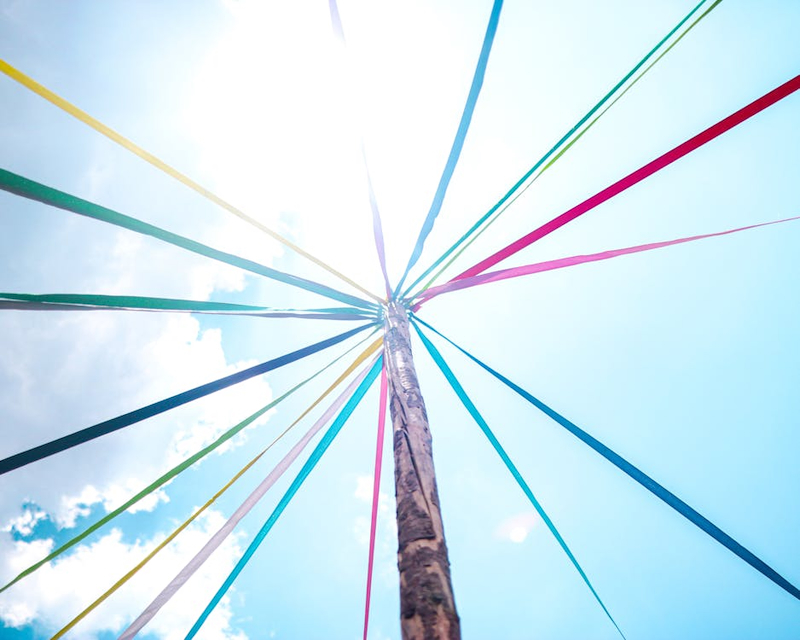 Looking up at the top of a pole from below, with colored ribbons radiating from the top.