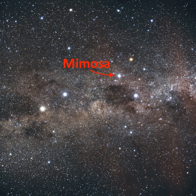 In starry sky, 4 bright stars forming a cross shape and 2 more out to the side, against a hazy glowing band.