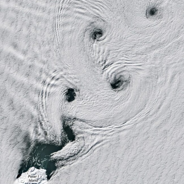 A white island at bottom left and clouds leaving from it in swirls with four eyes.