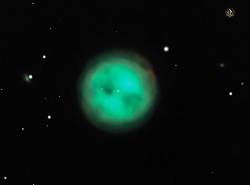 A large sphere of electric green gas resembling the face of an owl, surrounded by sparse stars.