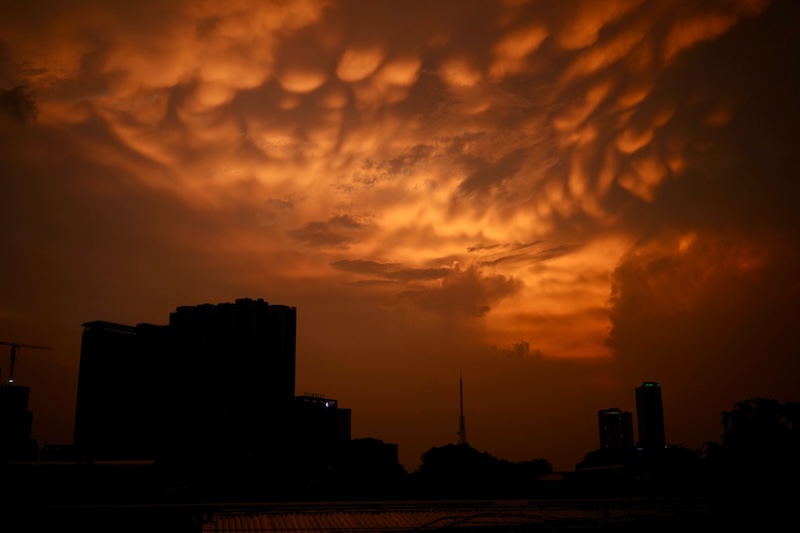 Dark orange sky with mammatus clouds with buildings in foreground.