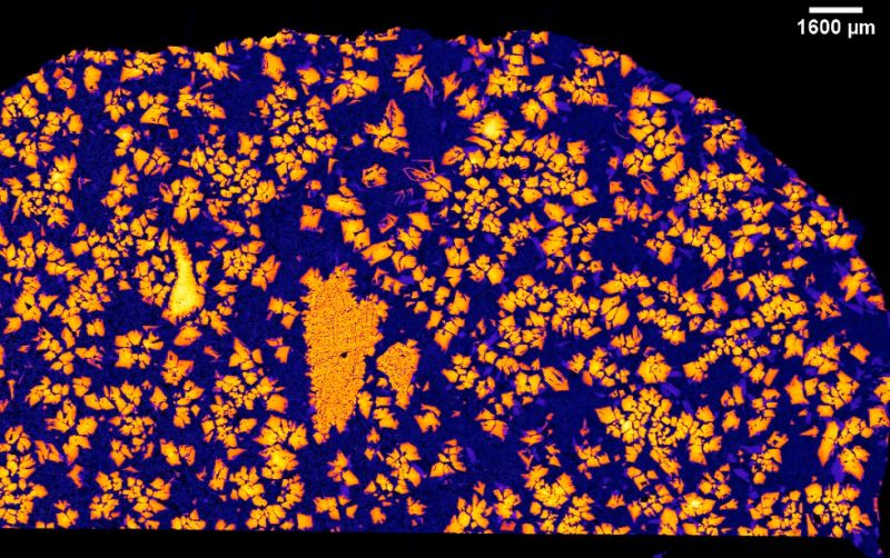A rock with many sharp-edged crystals in orange and the background in deep purple.