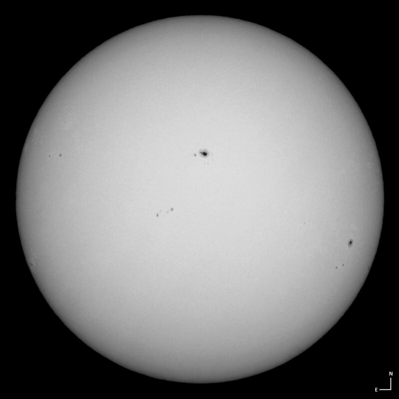 The sun, seen as a large white sphere with small dark spots.