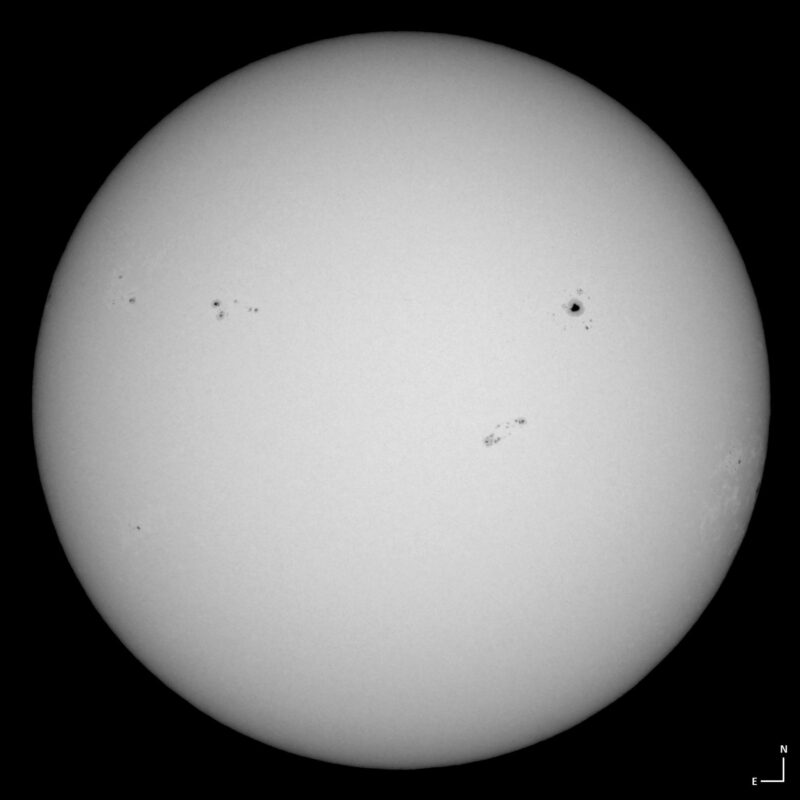 The sun, seen as a large white sphere with small dark spots.
