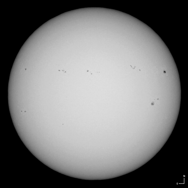 The sun, seen as a large white sphere with small dark spots.