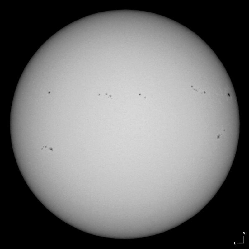 The sun, seen as a large white sphere with small dark spots.
