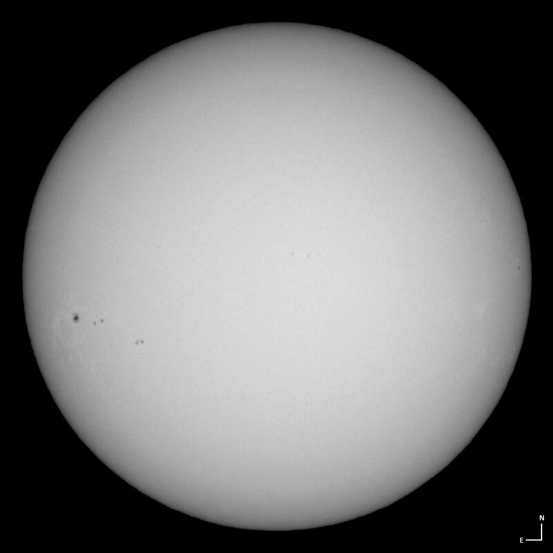 The sun, seen as a large white sphere with small dark spots.