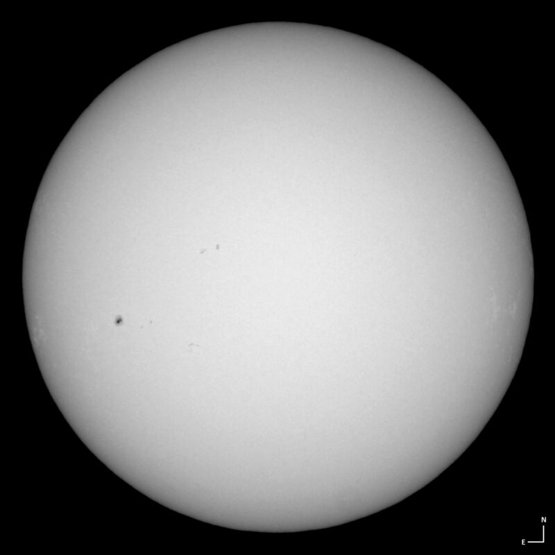 The sun, seen as a large white sphere with small dark spots.
