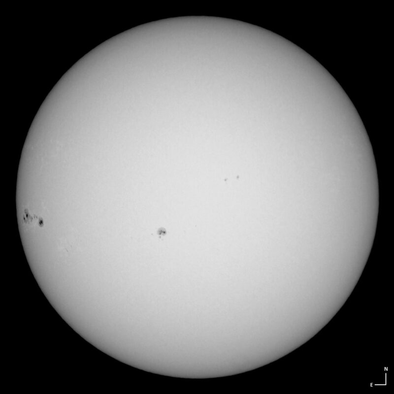 The sun, seen as a large white sphere with small dark spots.