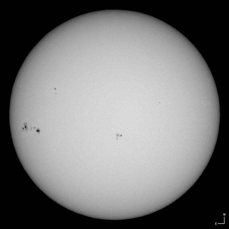 The sun, seen as a large white sphere with small dark spots.