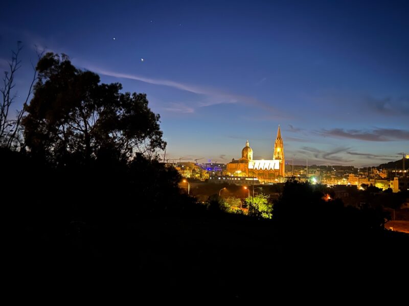 2 bright dots and 2 fainter dots above them. All over a city illuminated at night.