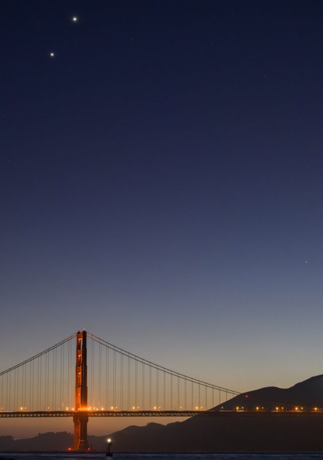 2 bright dots at the top left, and a very distant dot to the bottom right. They are above a large bridge.