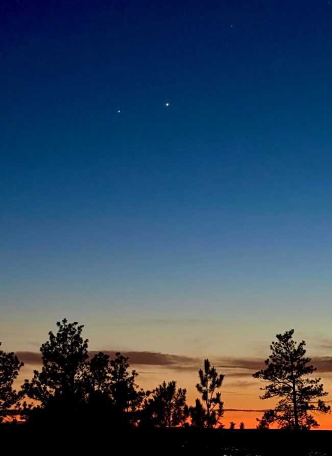 2 bright dots in a dark blue sky. The horizon looks deep orange.