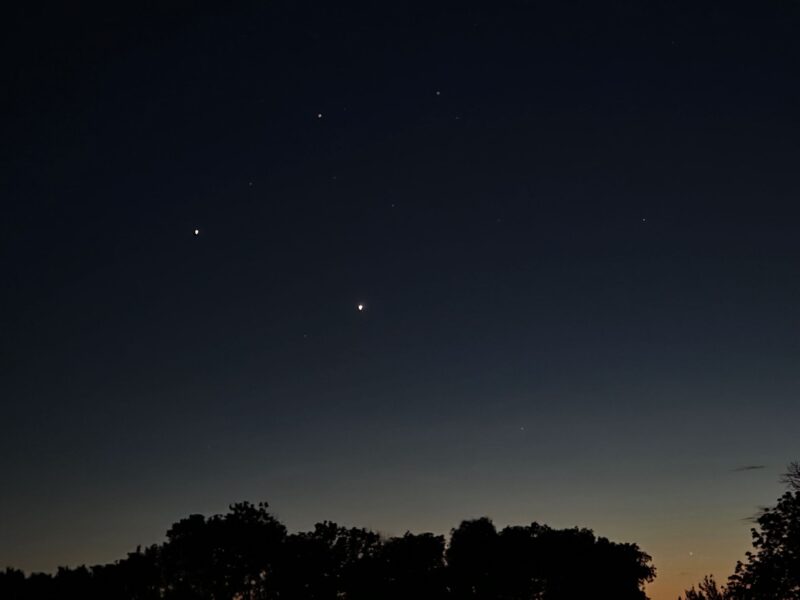 Dark sky with 2 very bright dots and some fainter dots around.