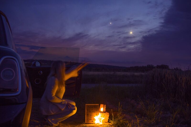 Venus-Jupiter conjunction: A woman pointing at 2 very bright dots in the sky. There are some purplish clouds around.