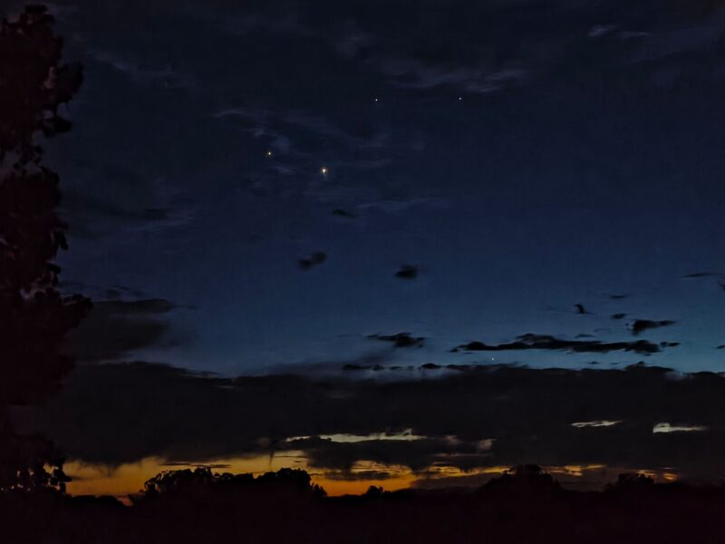 Layer of dark sky, then clouds, then orange horizon. Four bright dots in the dark sky.