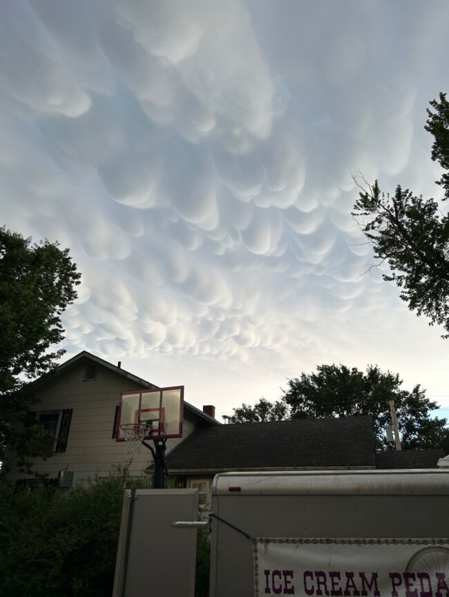 Many round, fluffy clouds above a house.