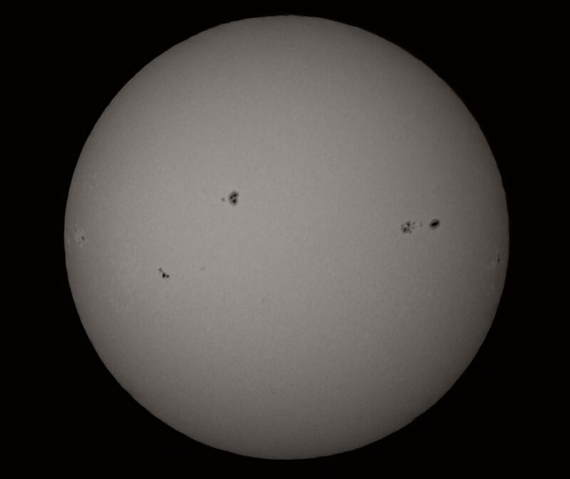 The sun, seen as a large gray sphere with small dark spots.