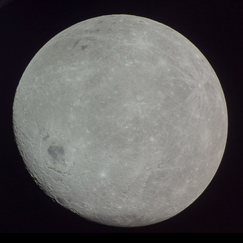 Far side full moon appearing smooth with no large craters and only 2 small dark splotches.