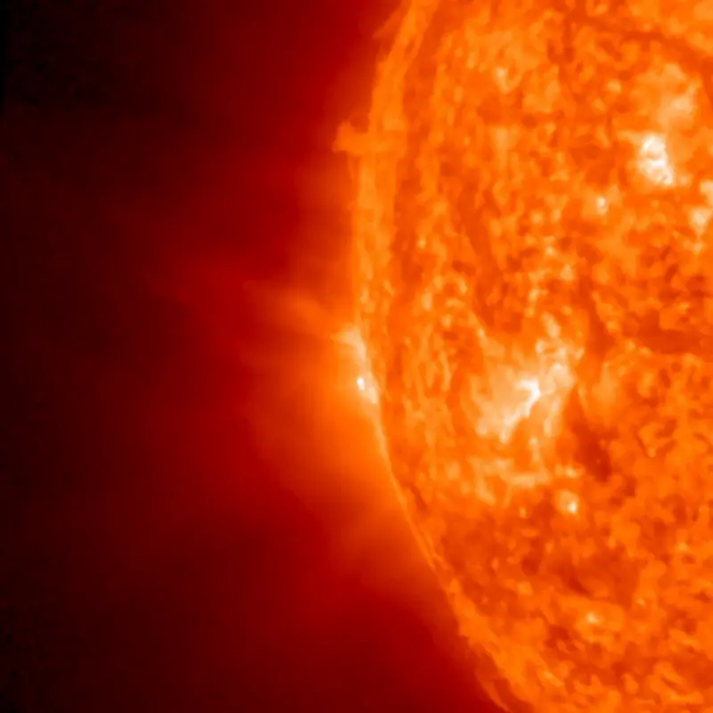 Part of the sun in mottled orange, with bright spots right at the horizon.