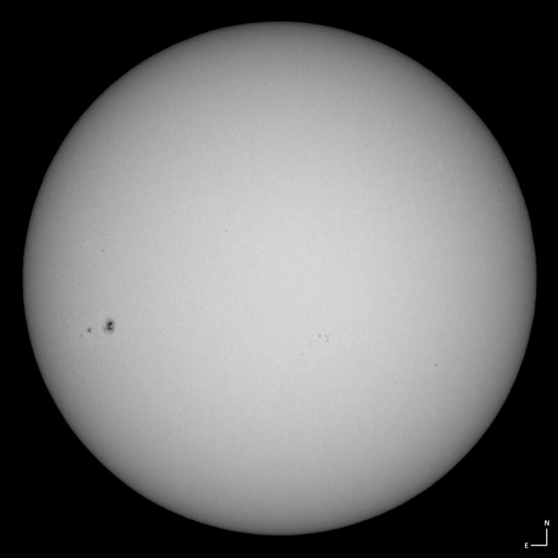 The sun, seen as a large white sphere with small dark spots.