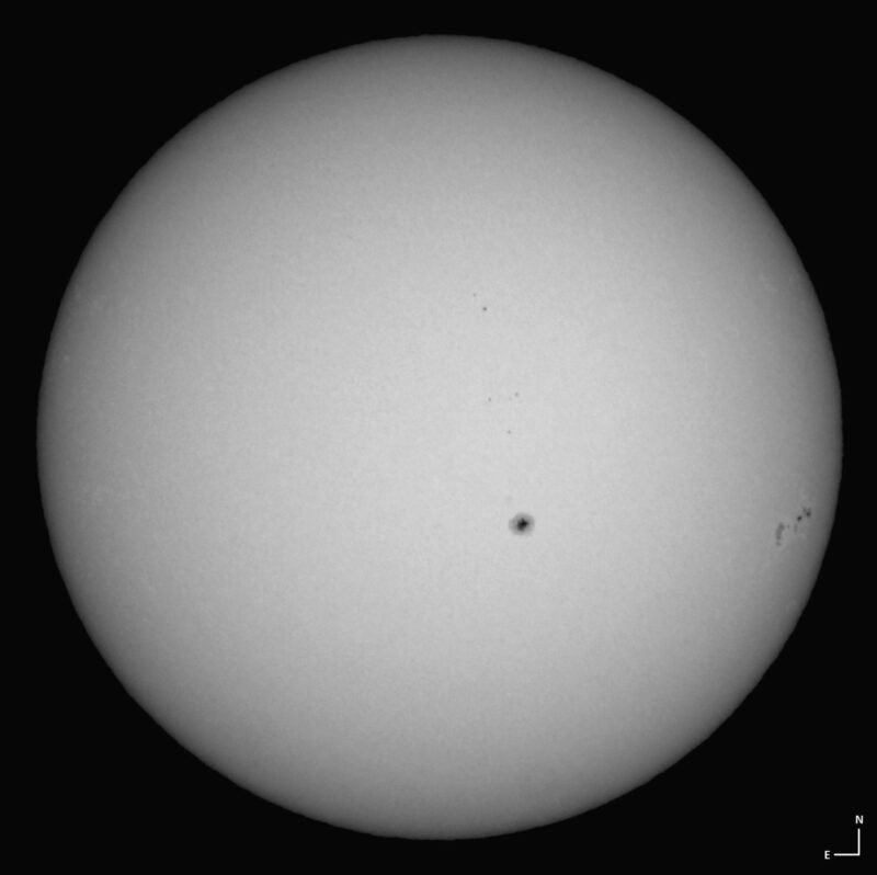 The sun, seen as a large white sphere with small dark spots.