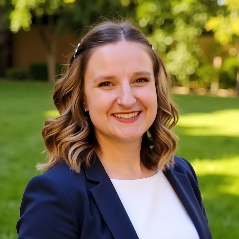 Smiling woman wearing a dark blue blazer and white shirt.