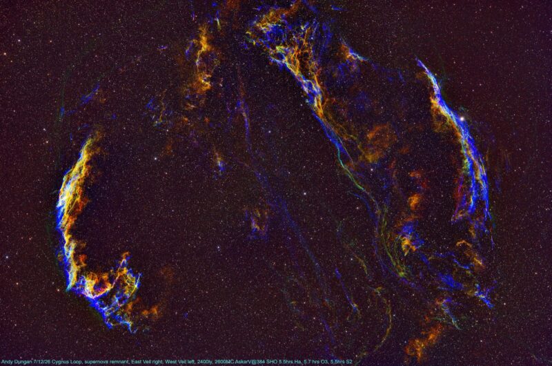 Two large, symmetrical, arc-shaped clouds of gas in bright gold and deep electric blue, with numerous background stars.