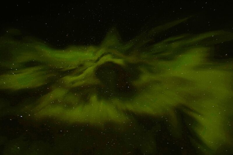 Radial green streaks of light in the dark sky.