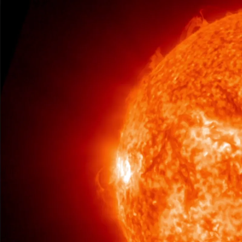 Huge flash on the edge of the sun with streamers of glowing gas flying out from it.