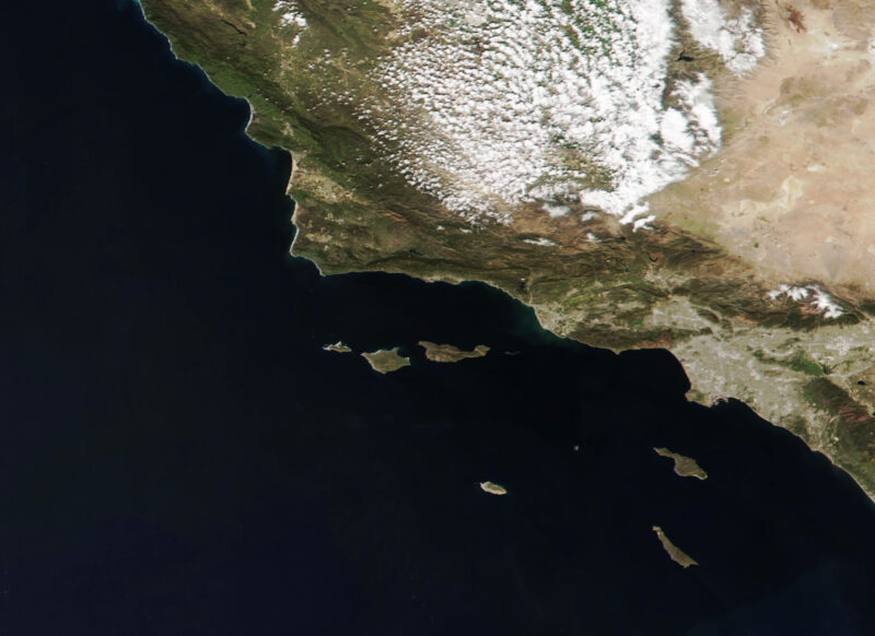 A landmass on the right with a handful of islands offshore surrounded by dark water.
