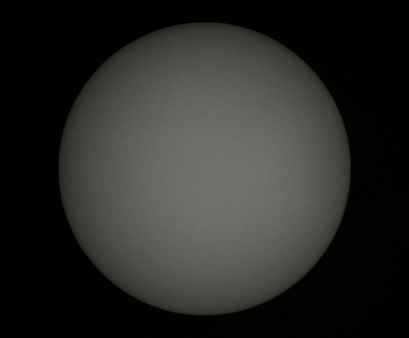 The sun, seen as a large gray sphere with small dark spots.