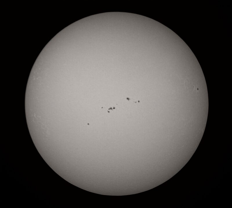The sun, seen as a large gray sphere with small dark spots.