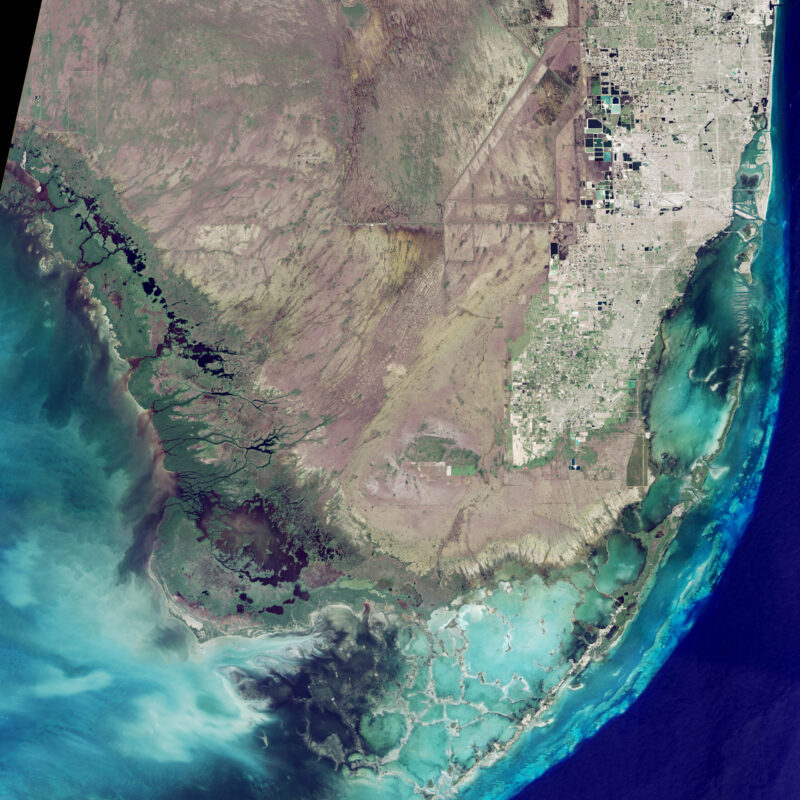 National parks from space: Water surrounding land on three sides with a chain of keys and lines for a city at right.