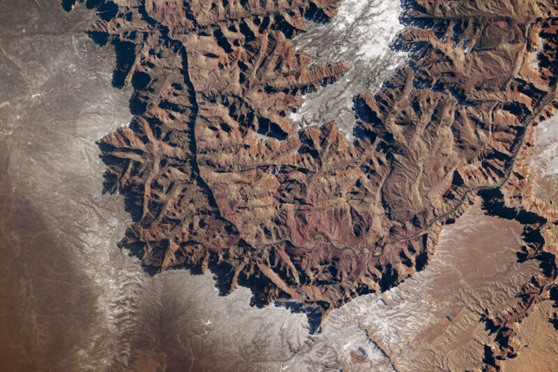 A deep canyon with many branches colored in reds and tans.