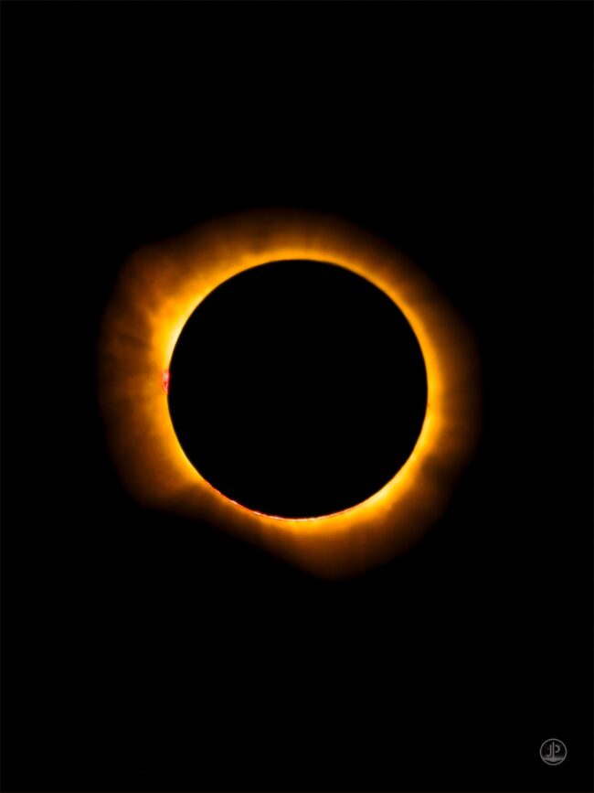 A large solid black disk surrounded by a luminous aura of golden light.