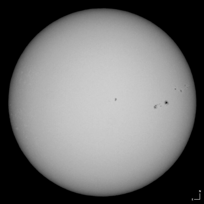 The sun, seen as a large white sphere with small dark spots.