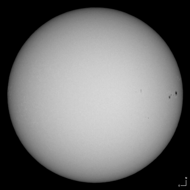 The sun, seen as a large white sphere with small dark spots.