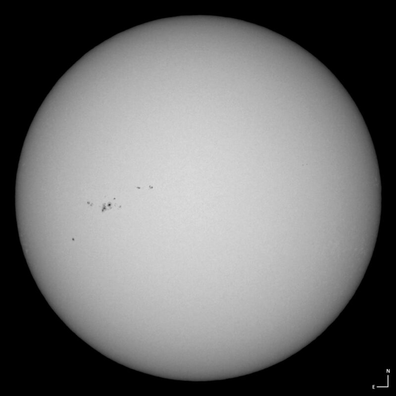 The sun, seen as a large white sphere with small dark spots.