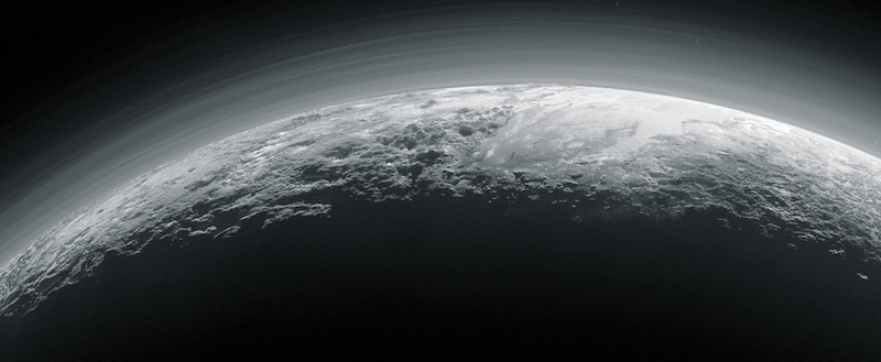 Black and white image of the limb of a planet in sunlight, with haze above the surface.