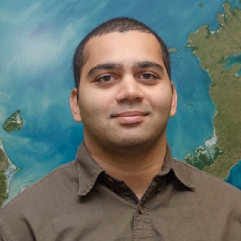 Smiling man with dark complexion and very short hair.