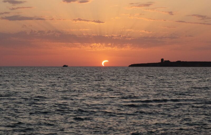 A bright solar crescent setting down right above the ocean.