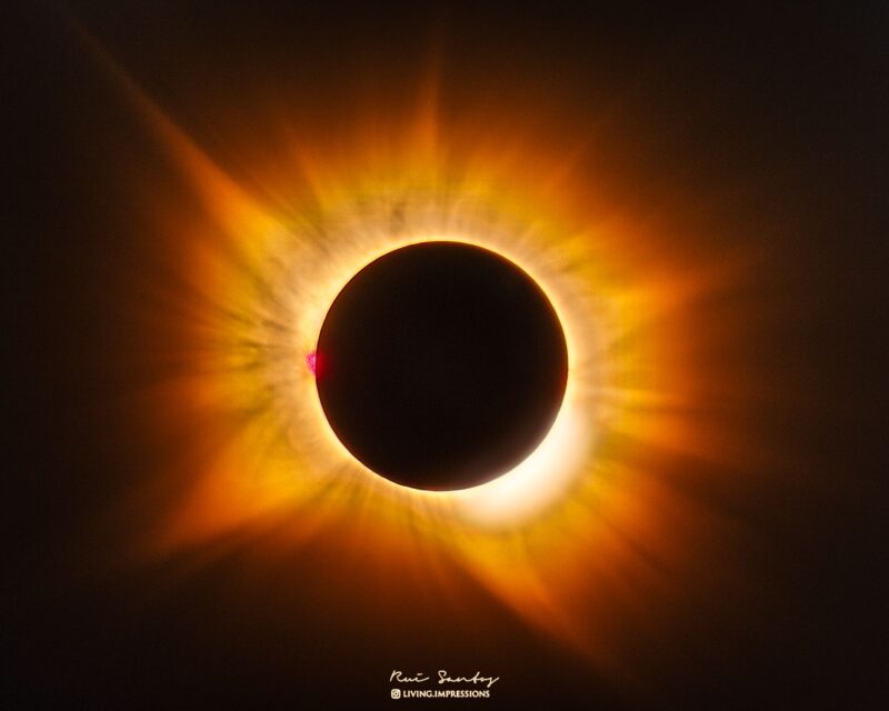 A large solid black disk surrounded by a luminous aura of golden light.