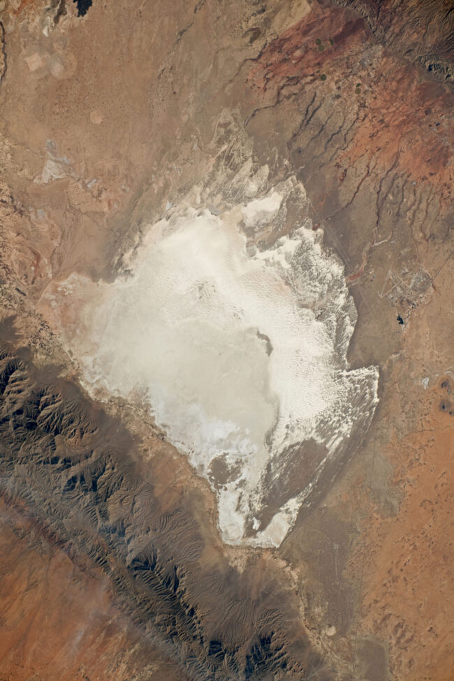 Tan landscape with mountains at lower left and a big area of white in the middle.