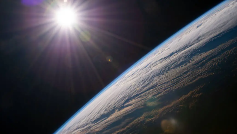 Do the planets revolve around the sun? Earth close at bottom right with bright sun upper left.
