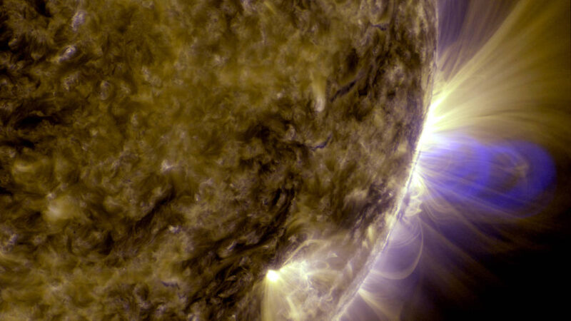 Close-up view of the sun showing bright, looping magnetic structures and glowing plasma extending above the solar limb.