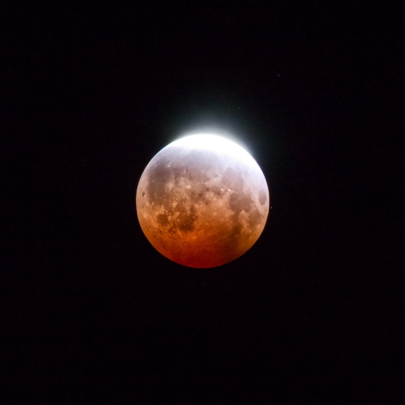 The deep orange moon with a slice of glowing white at the top.