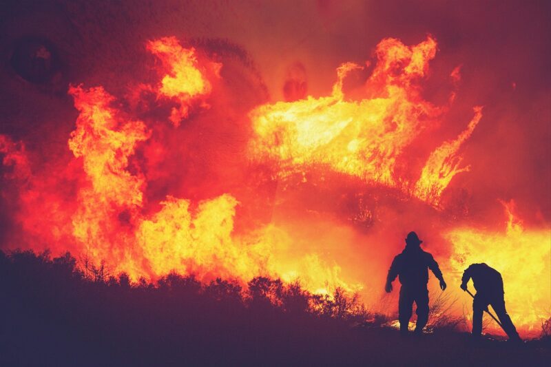 Spokane wildfires: A wall of flame with two firefighters in silhouette.