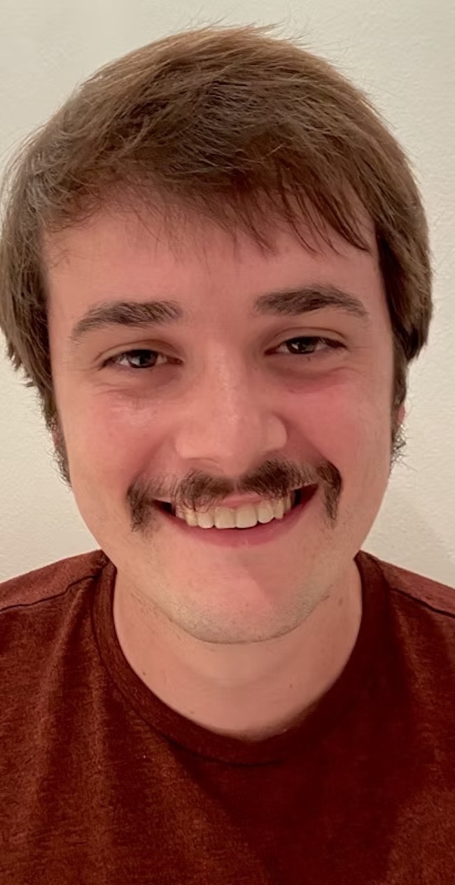 Smiling man with handlebar moustache.